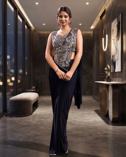 Model wearing a black ready-to-wear saree with a sleeveless embellished blouse and an asymmetric decorative front panel.